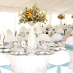 Elegant indoor wedding setup with white linen and blue sashes at Moholoholo’s riverside venue in the Lowveld near the Drakensberg.