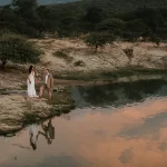 Bride and groom by the water at Moholoholo Ya Mati wedding venue, with Drakensberg backdrop, a romantic bush wedding location in Hoedspruit.